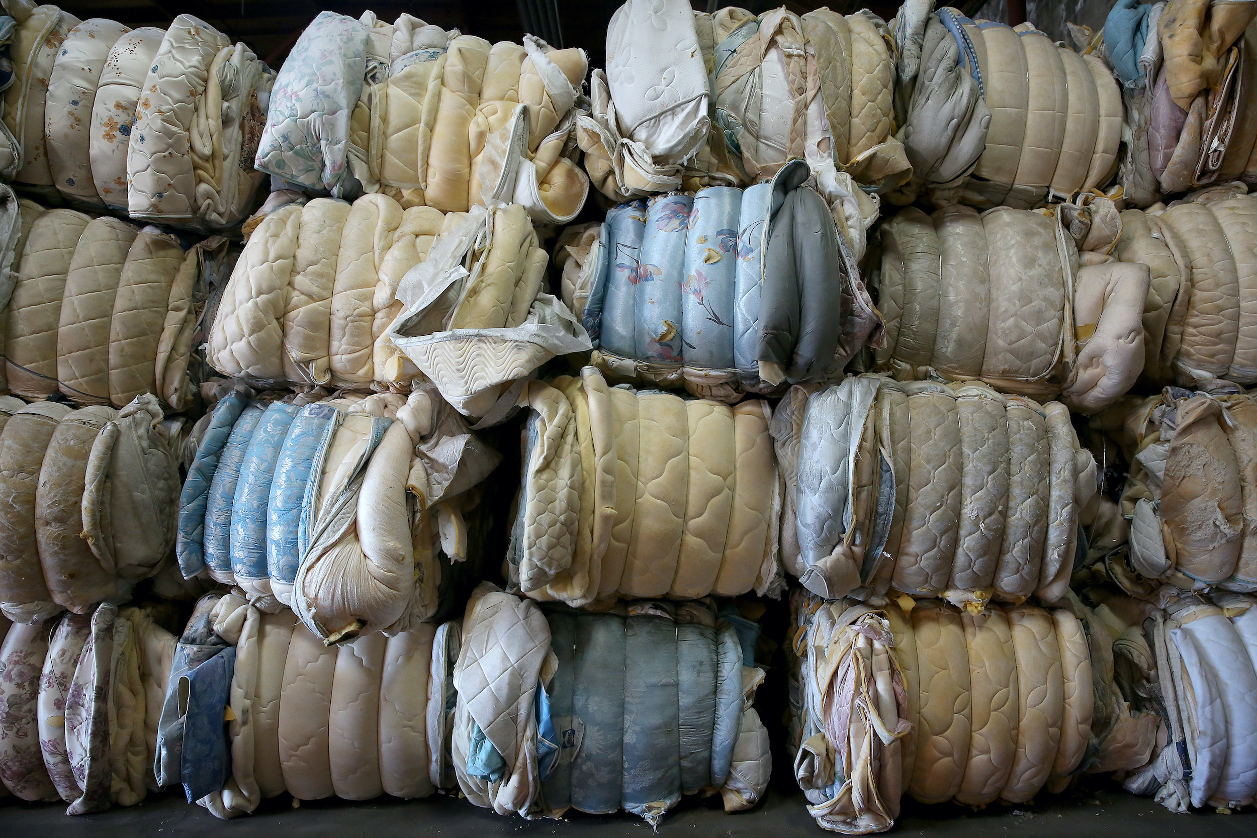 Mattresses are rolled and stacked in a pile in a warehouse in California.