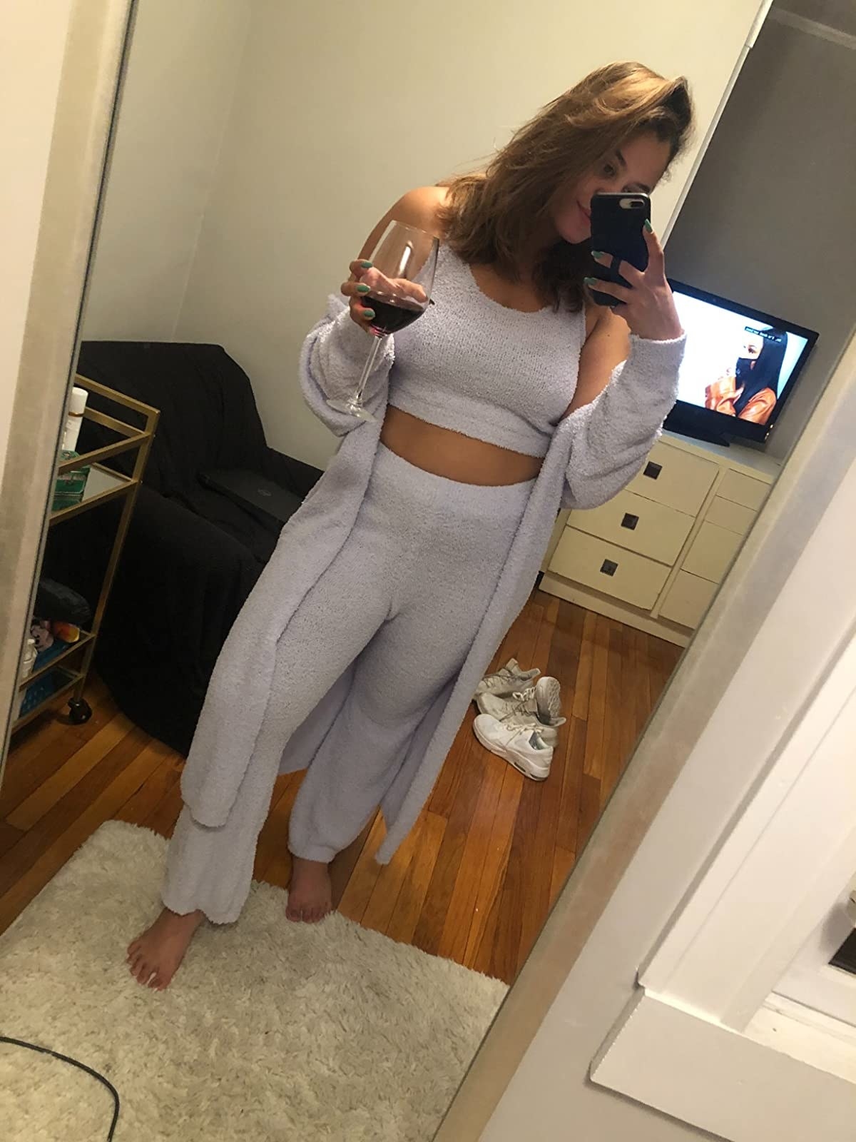 reviewer wearing the three piece set while holding a glass of red wine
