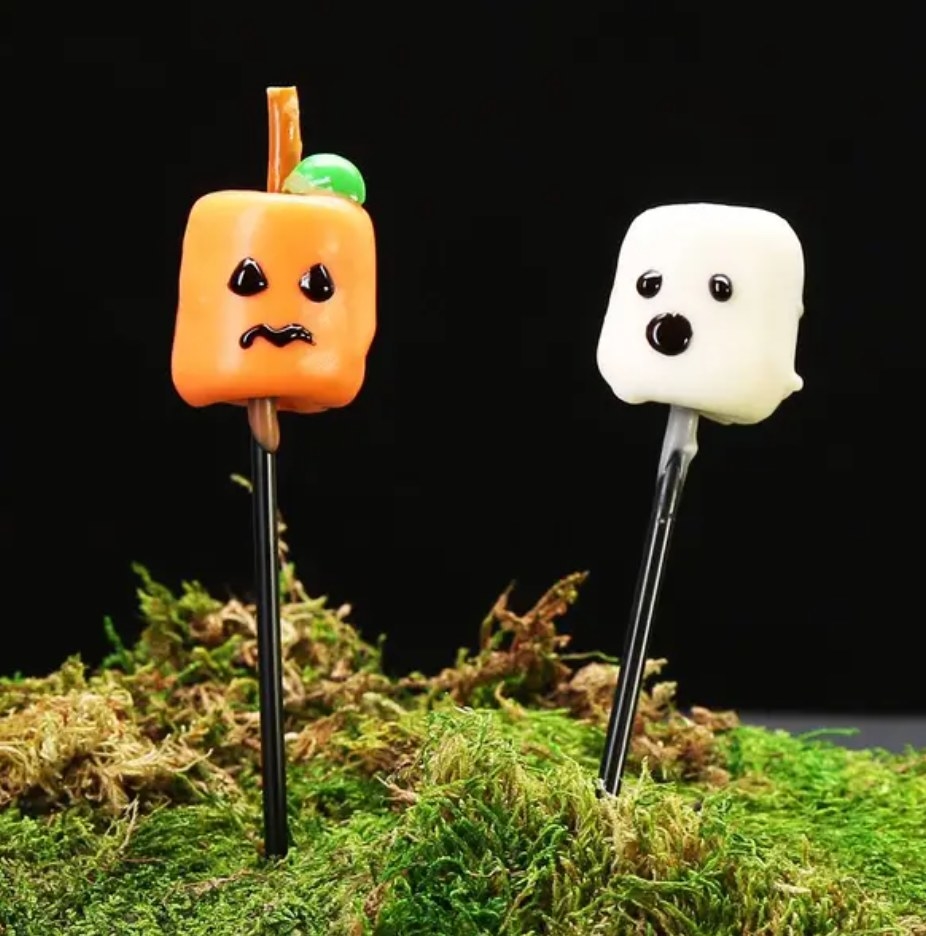 two marshmallows on skewers decorated as a pumpkin and a ghost