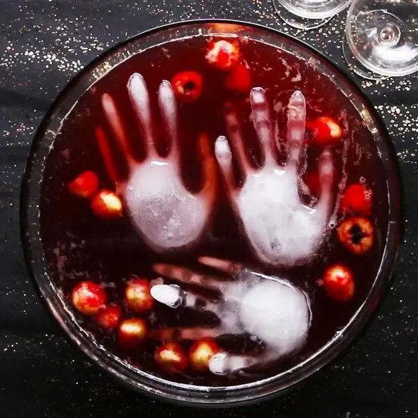 punch bowl with red fruit and hand-shaped ice cubes