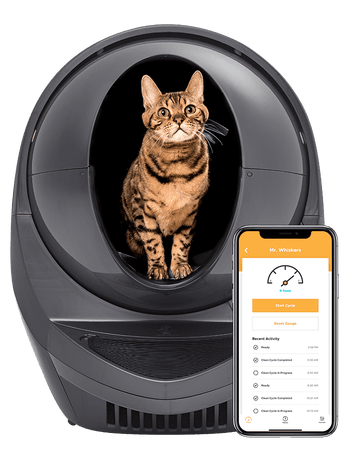 A cat sitting in a Litter Robot next to a phone showing the Litter Robot app