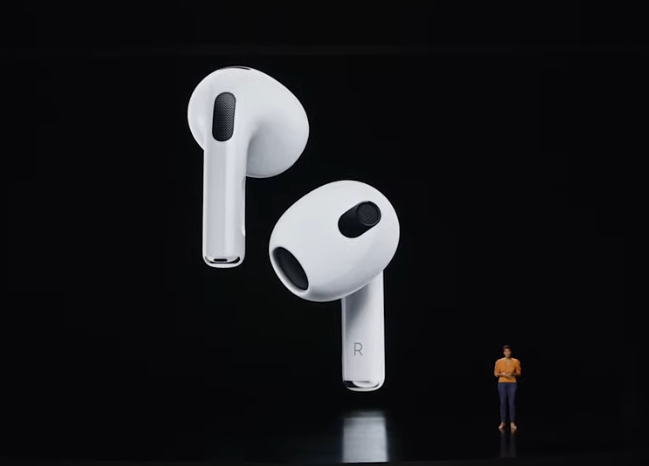 The new AirPods onscreen behind a presenter