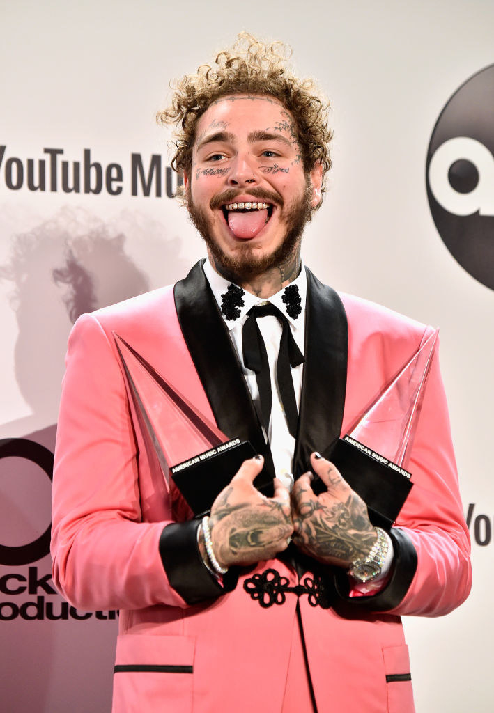 Post Malone holding awards and sticking his tongue out