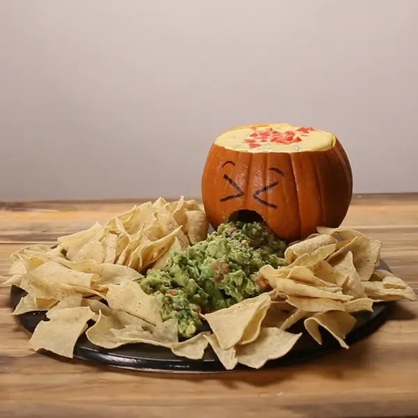 chips platter featuring guacamole in the center and a pumpkin filled with queso