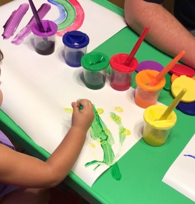 Reviewer's child painting with the colorful paint cups sitting on the table