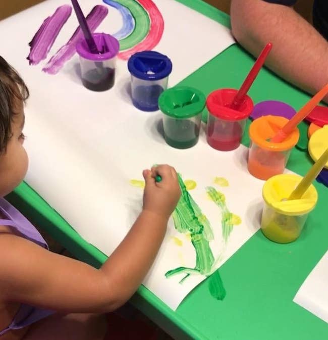 Reviewer's child painting with the colorful paint cups sitting on the table