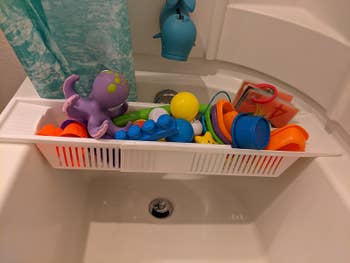 Reviewer's photo showing the bathtub caddy holding their kids' toys