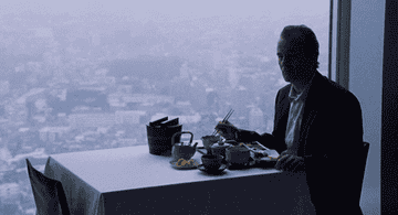 Bill Murray as Bob Harris eats alone at a table next to a beautiful view of Tokyo in &quot;Lost in Translation&quot;