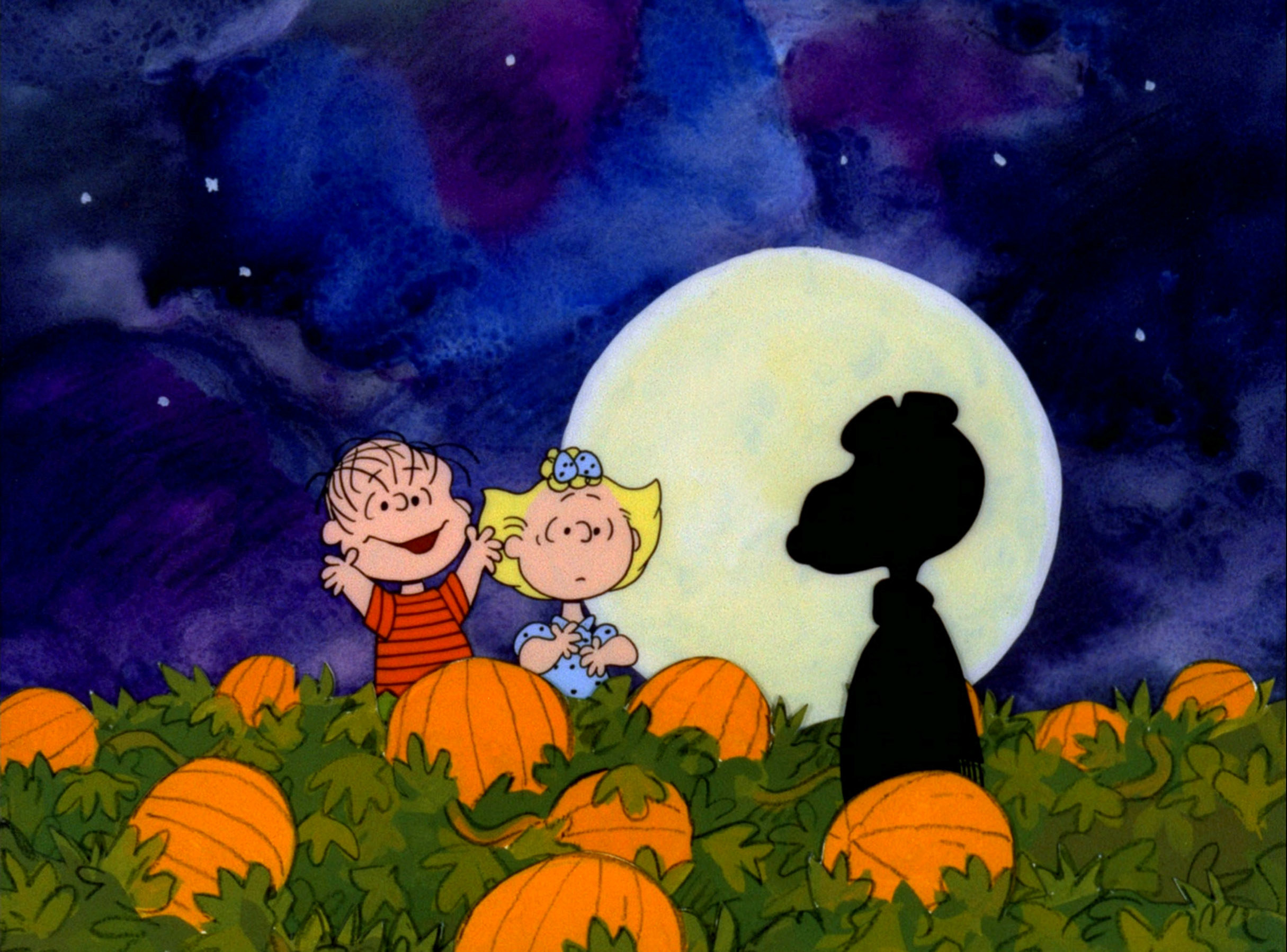 Linus, Sally, and Snoopy standing in a pumpkin patch
