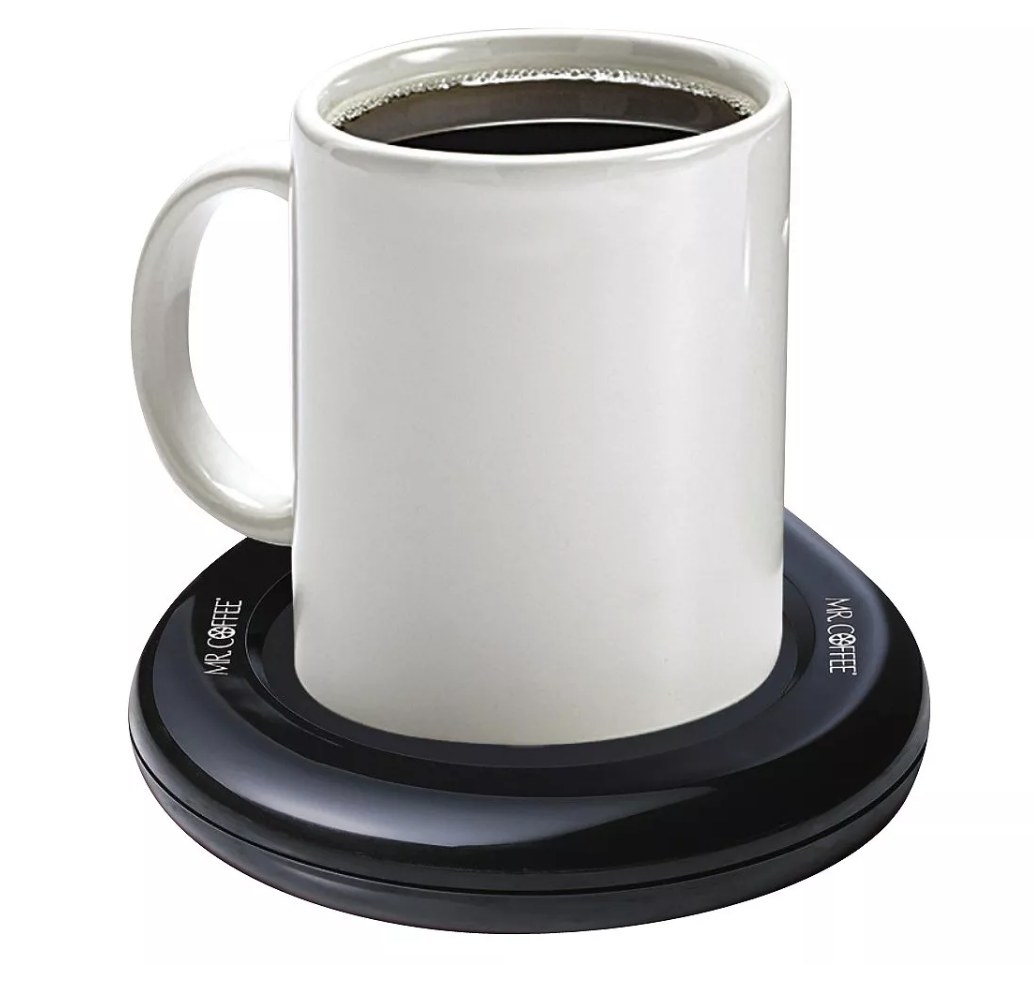 White mug of coffee on black coffee warmer