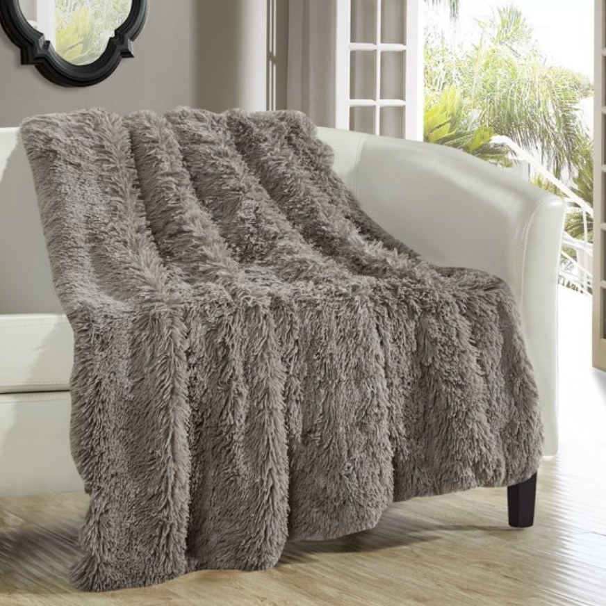 A silver faux fur blanket draped over a sofa