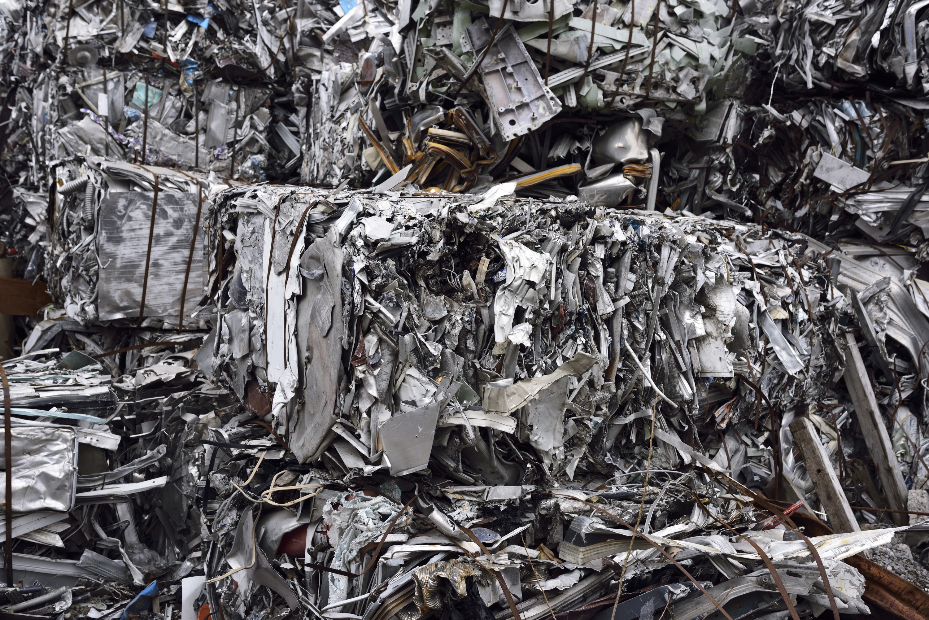 Metal is seen smashed and packed in a refuse site