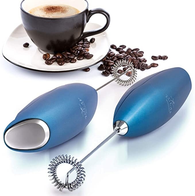 Blue milk frother next to cup of coffee with scattered coffee beans