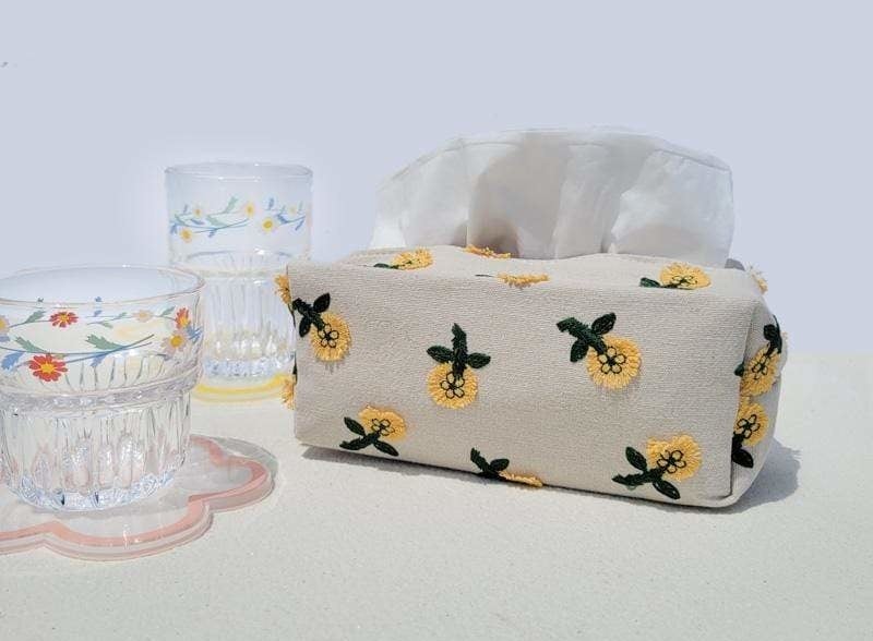 A fabric tissue box with cups beside it