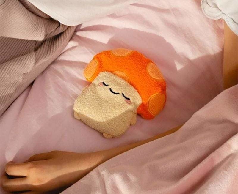 A small plush in the shape of a mushroom lying on a bed