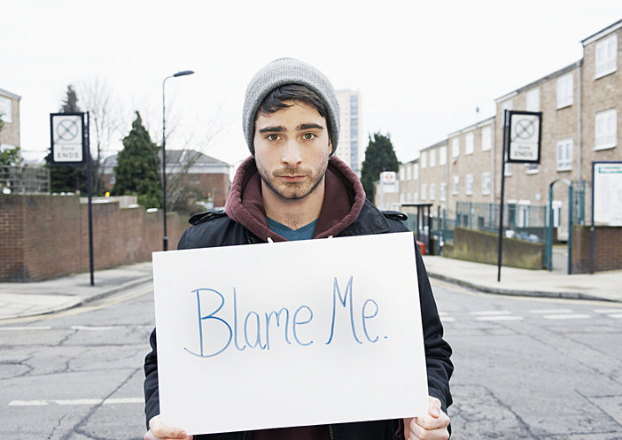 Young man holding sign that says &quot;Blame Me&quot; in urban street