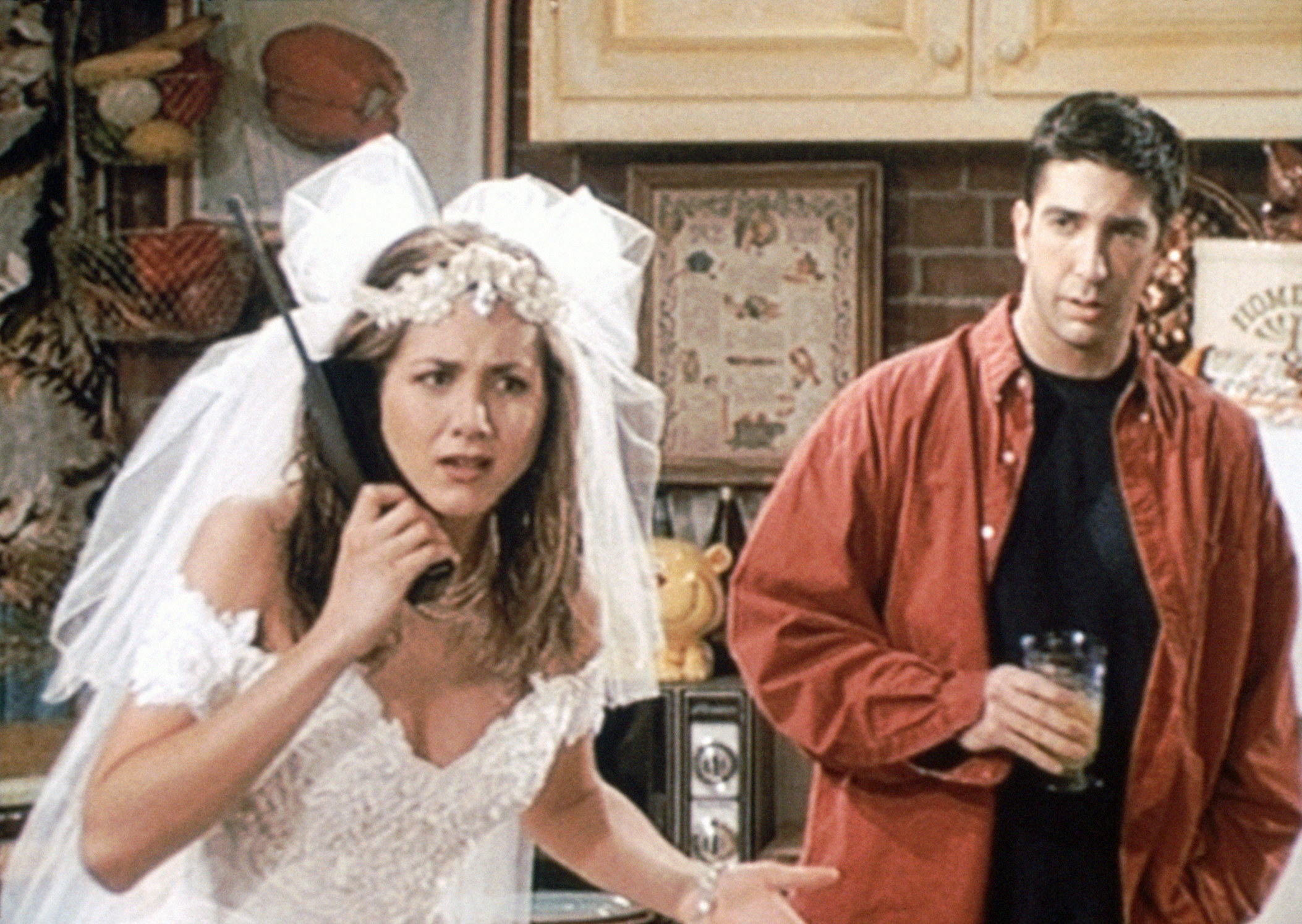 Rachel in her wedding dress on the phone while Ross watches