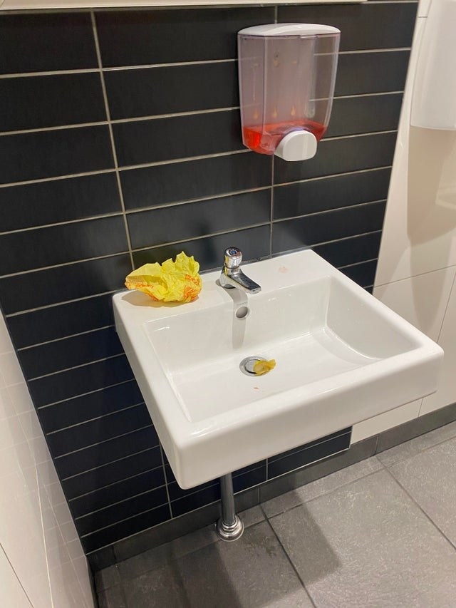 A cheeseburger wrapper left on the bathroom sink inside a McDonald&#x27;s bathroom