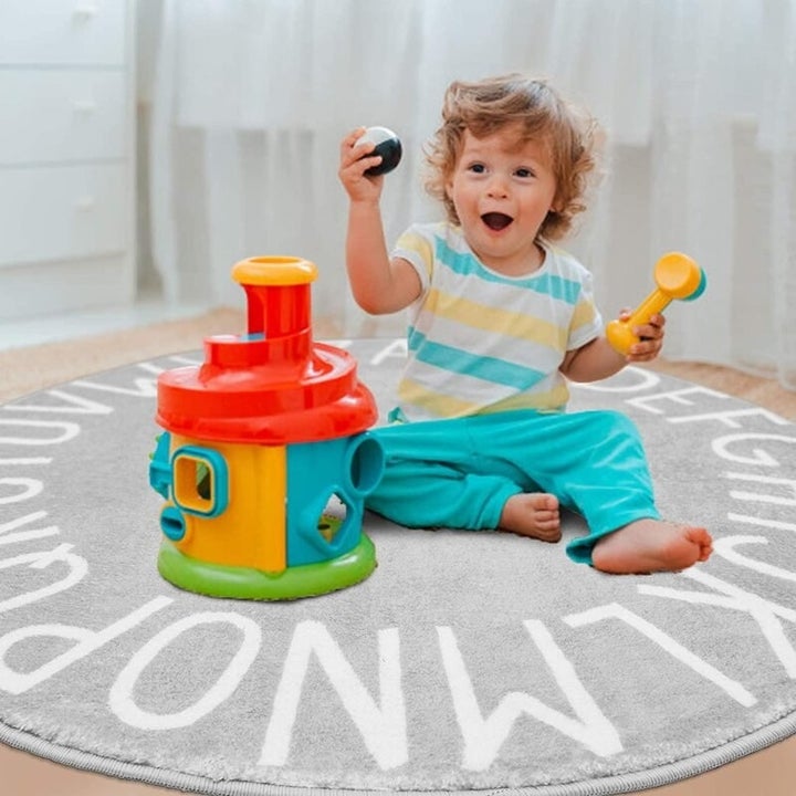 a child playing on the rug with colorful toys