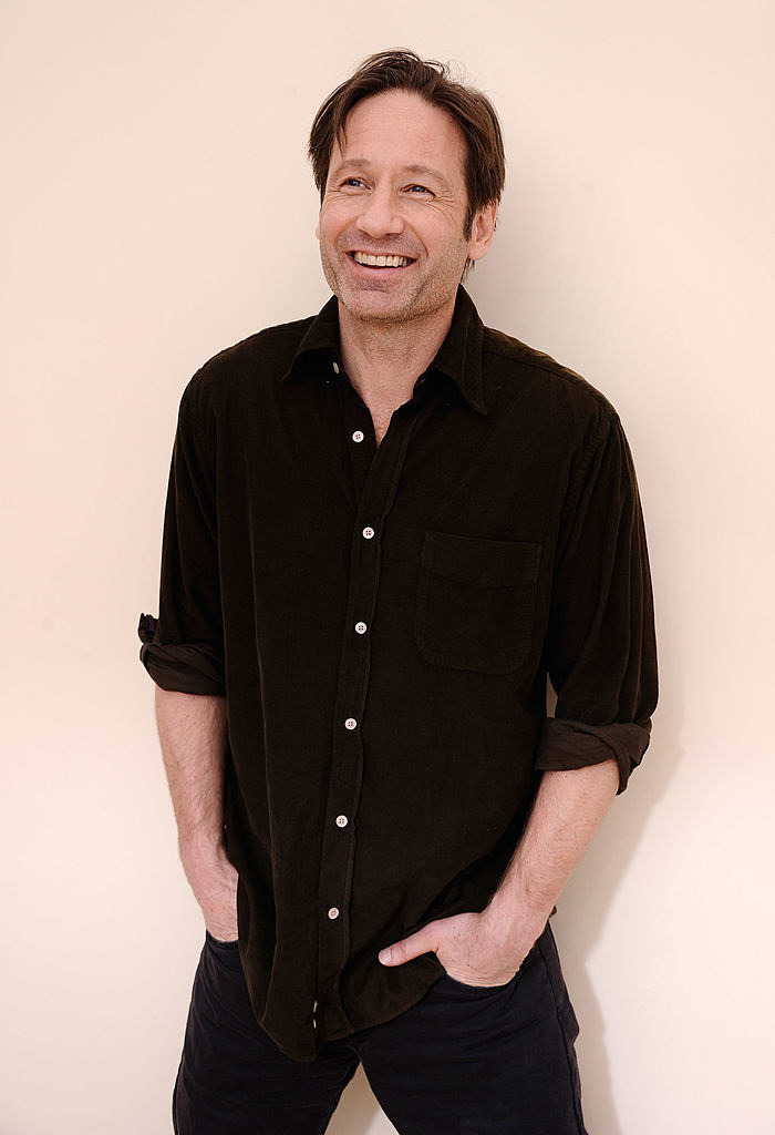 David Duchovny smiles and poses with his hands in his pants pockets for a portrait during the 2012 Sundance Film Festival