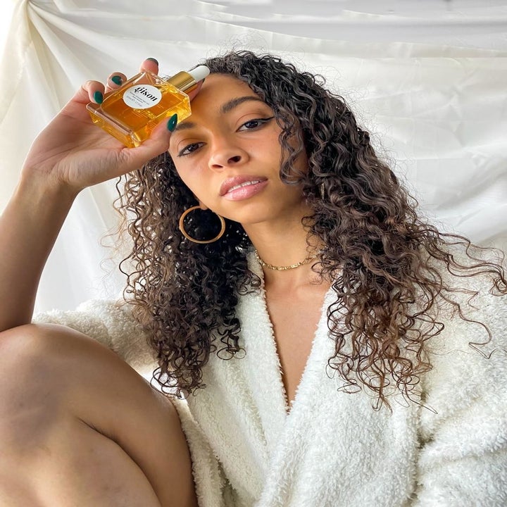 Reviewer photo of herself holding the hair oil bottle