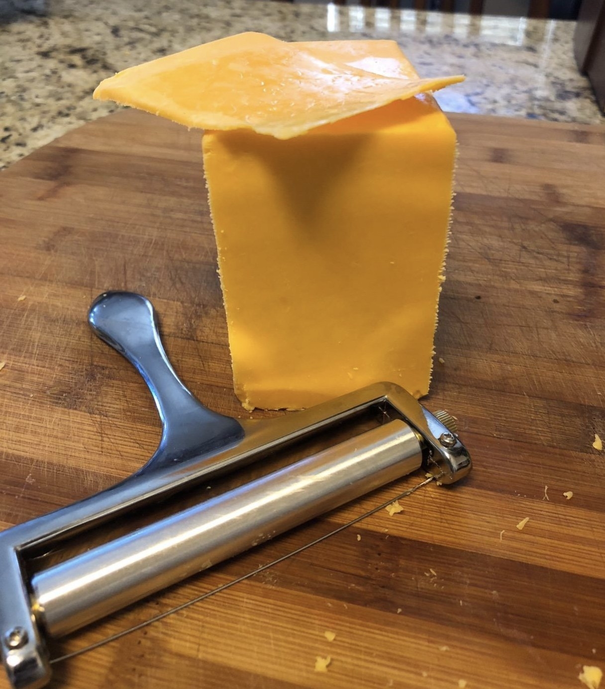 reviewer photo showing the cheese slicer next to a block of cheese