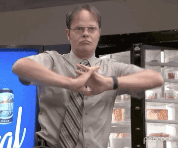 A close up of Dwight Schrute as he stretches his arms out