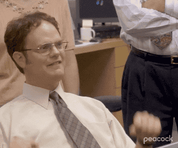 A close up of Dwight Schrute as he throws his fists up in celebration
