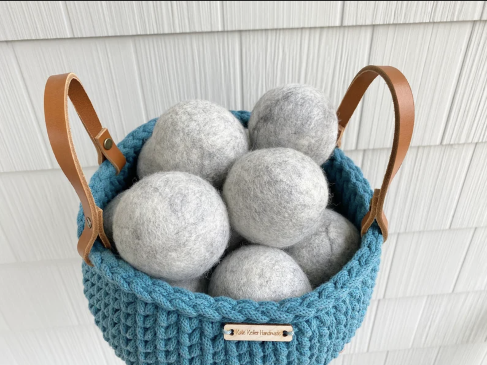 A bag of the grey dryer balls are shown in a blue basket