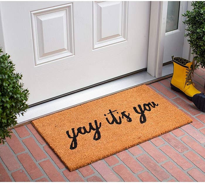 "Yay It's You" welcome mat in front of a door