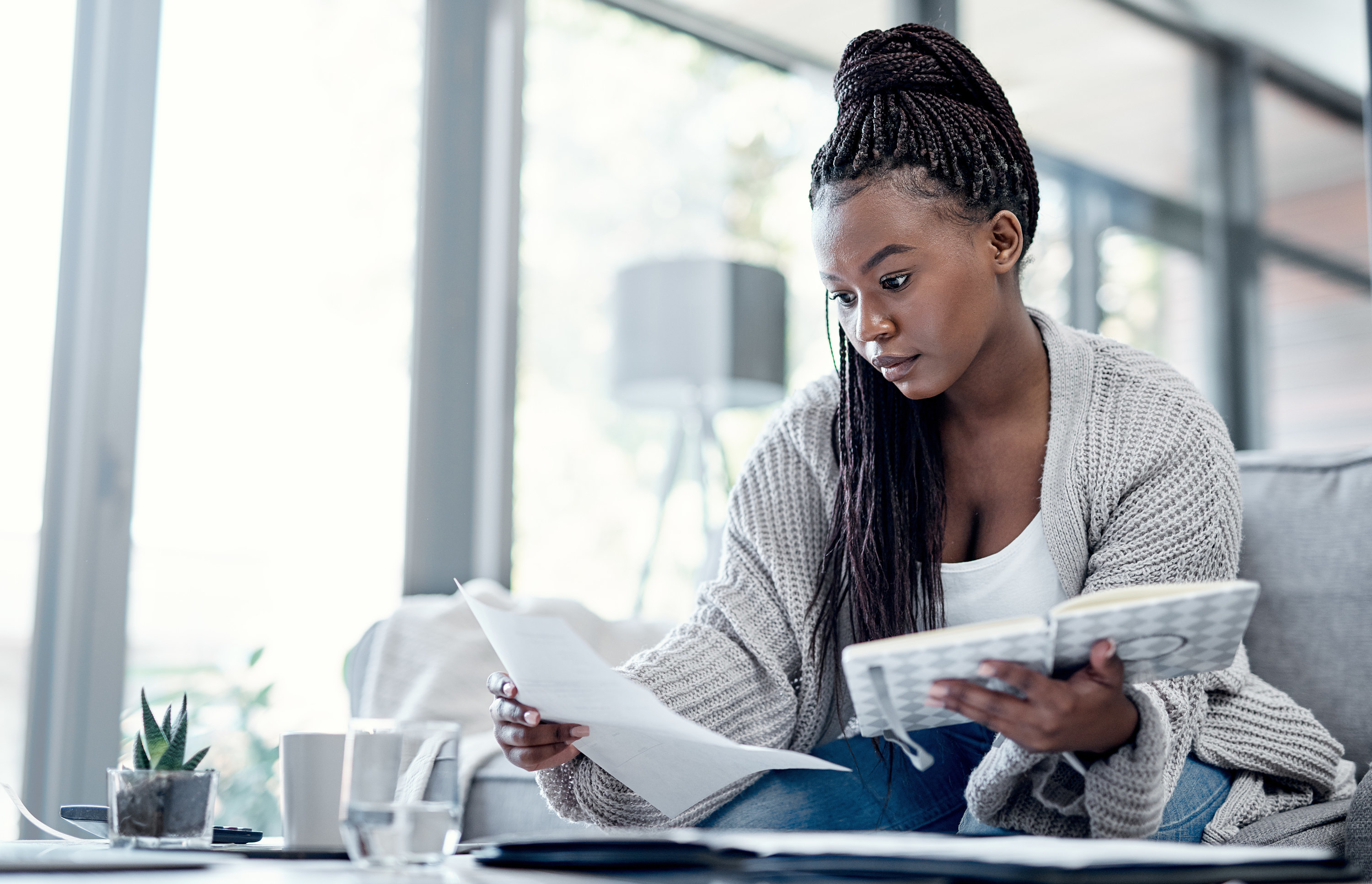 Woman on couch looking over financial statements