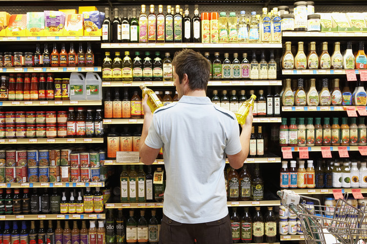 Man holding two bottles in a grocery aisle