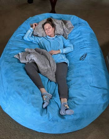 Reviewer sleeping on the blue bean bag sofa