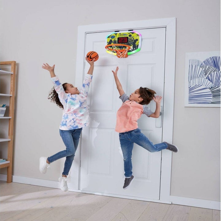 two children playing with the basketball hoop together and the hoop is hanging on the back of the door
