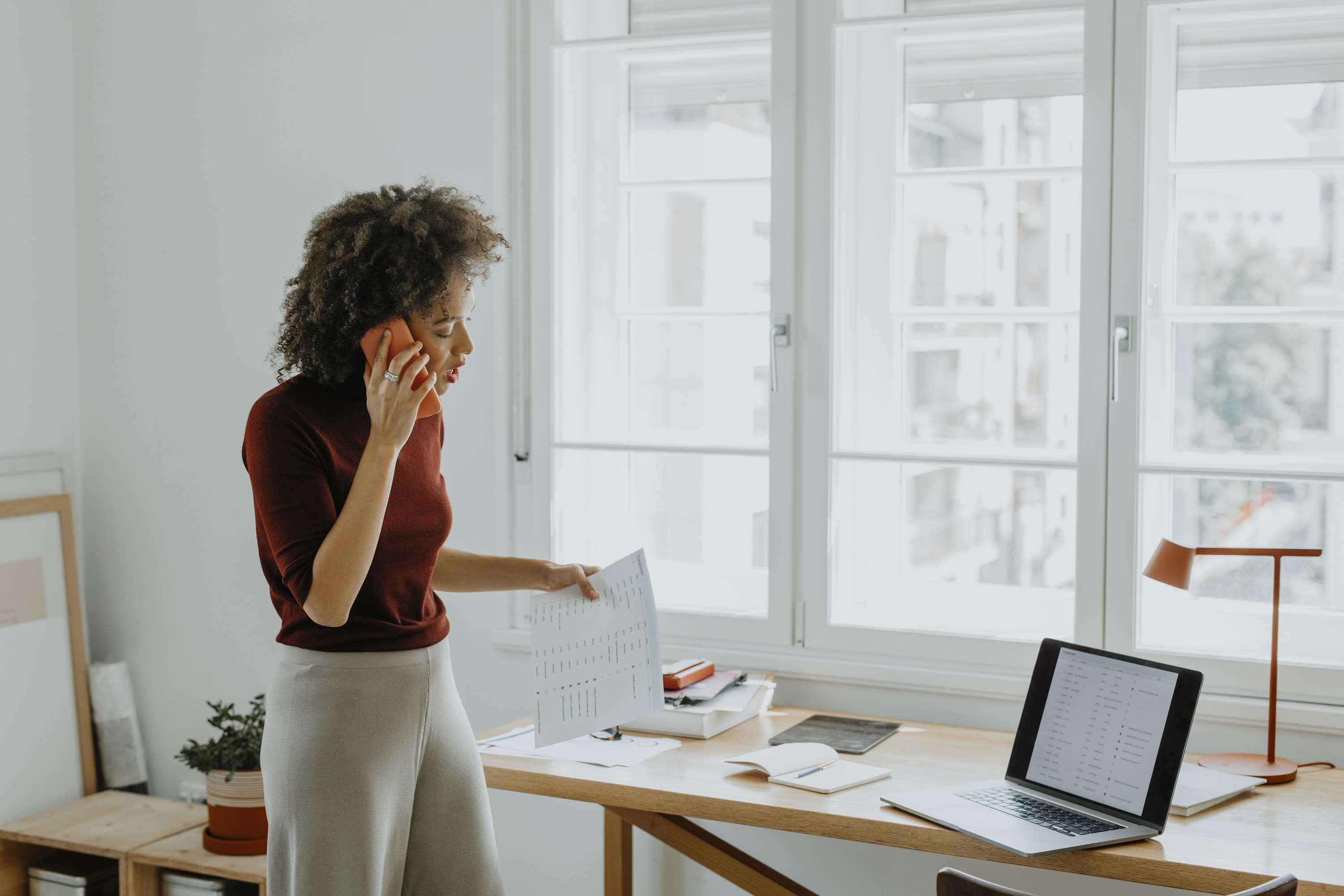 Woman getting questions answered over the phone will standing in her office