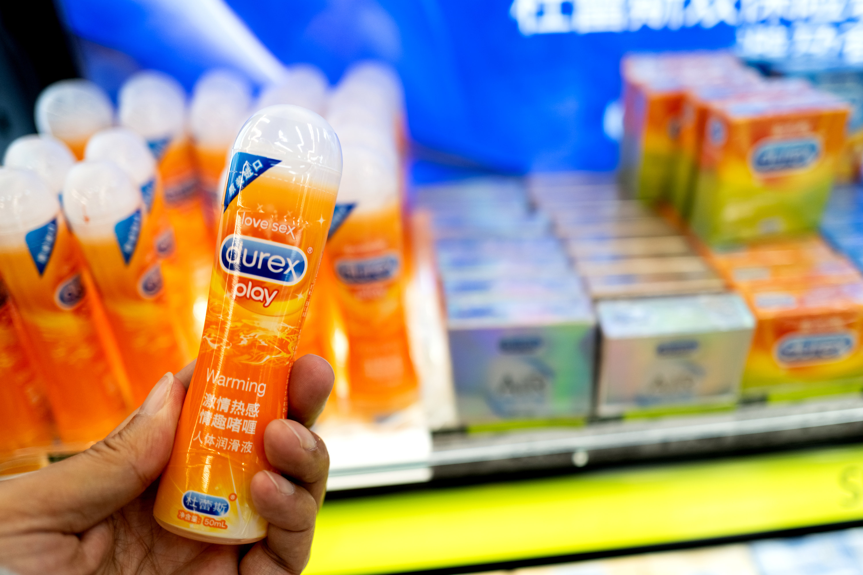 A person holding a tube of Durex brand lubricant in a store