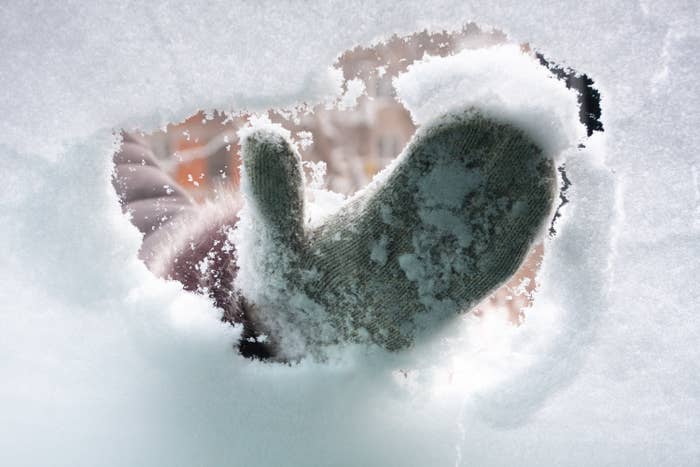 A mitten wipes away snow on a window.