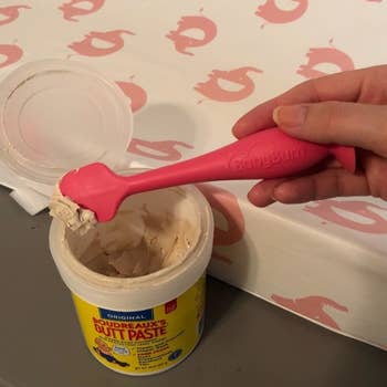 Reviewer holding the pink applicator over a jar of cream