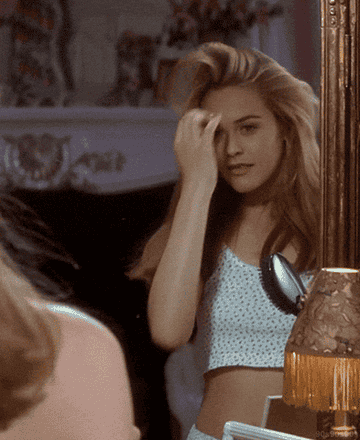 Cher finger-brushing through her hair in the mirror in Clueless