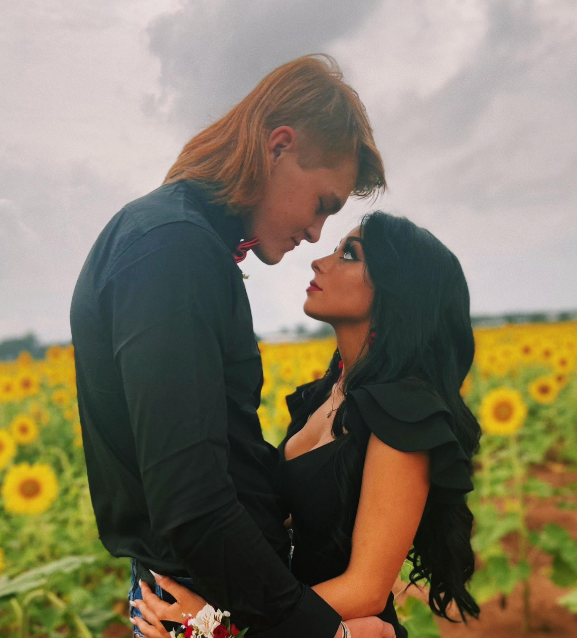 Zach and Grace gazing at each other amid sunflowers