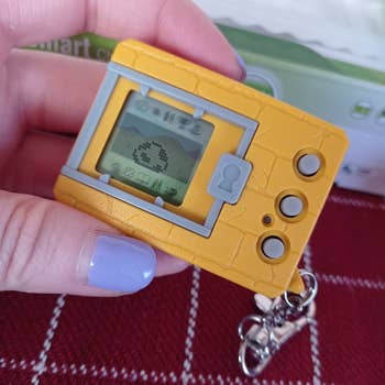 a yellow and gray digimon with a monster egg on the screen