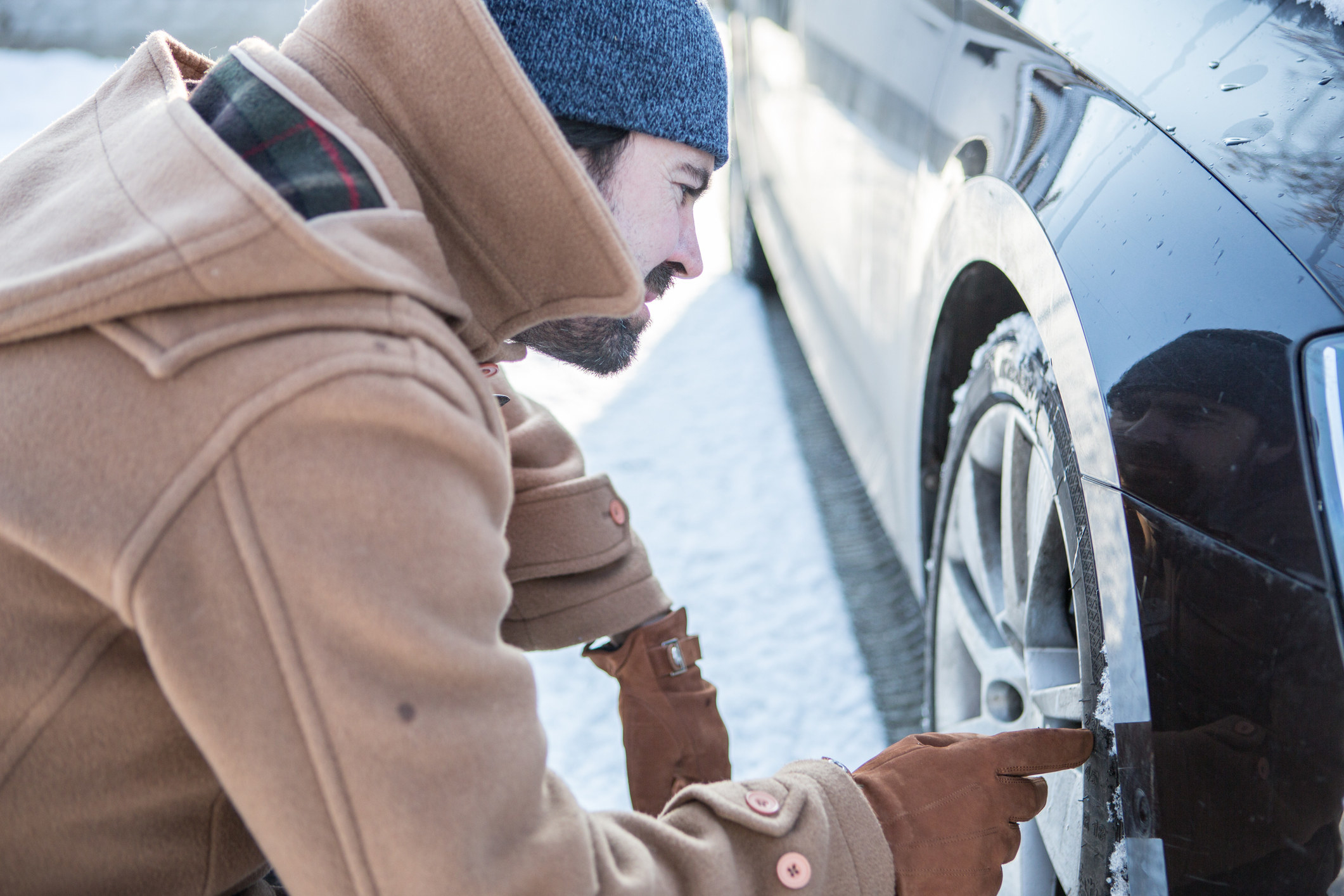 A man checks the state of his tires in the snow.