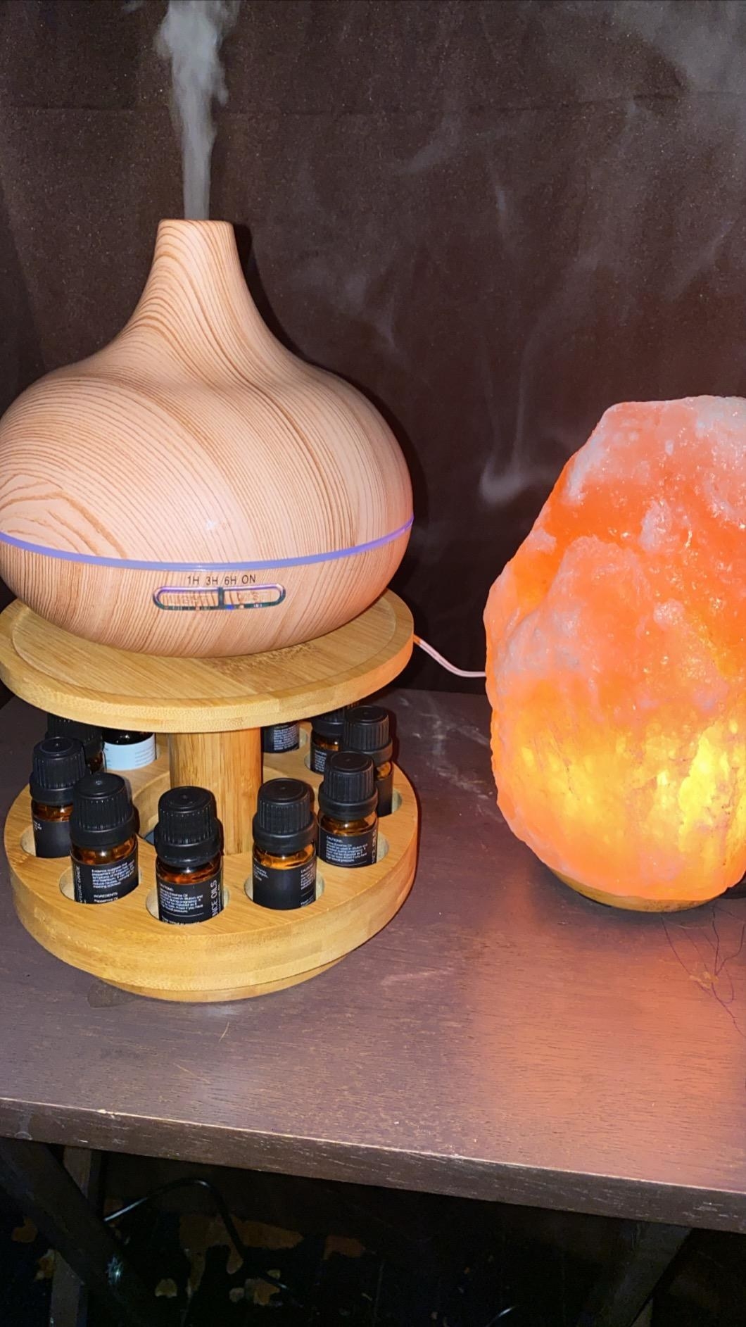 Reviewer photo of the oil diffuser with the essential oils next to a rock salt lamp