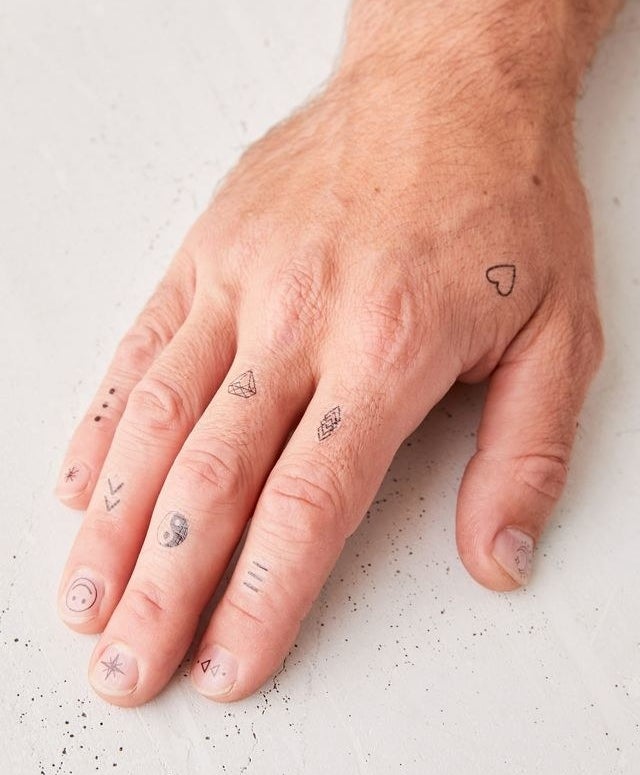 a close up of a person&#x27;s hand decked out in the mini temporary tattoos