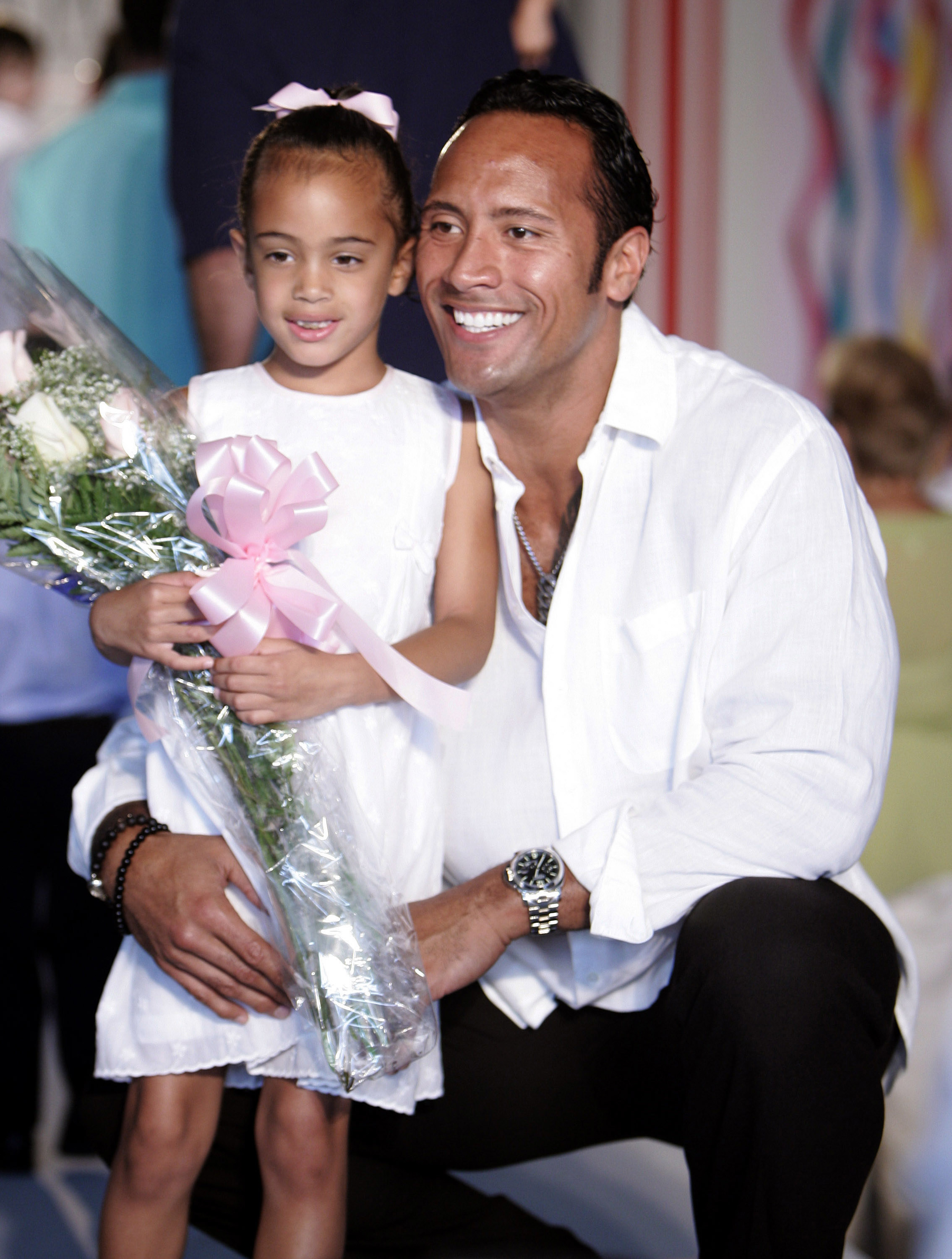 simone holding flowers as her dad bends down to hold her for a photo