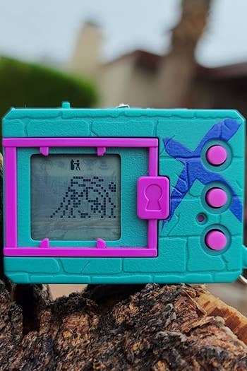 a digimon in teal and purple with a little person on the screen