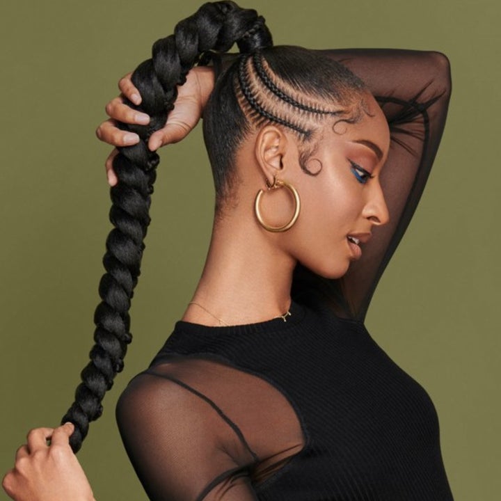 A model holding the end of her ponytail and showing off sleek edges