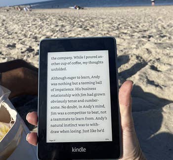 a reviewer reading from their kindle while on the beach