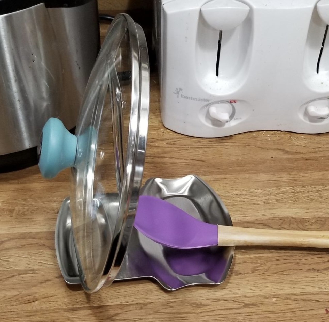 reviewer photo showing the holder with a spatula and a pot lid resting neatly on it