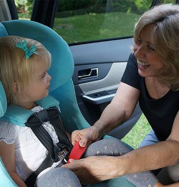 Adult securing child in car seat for safety